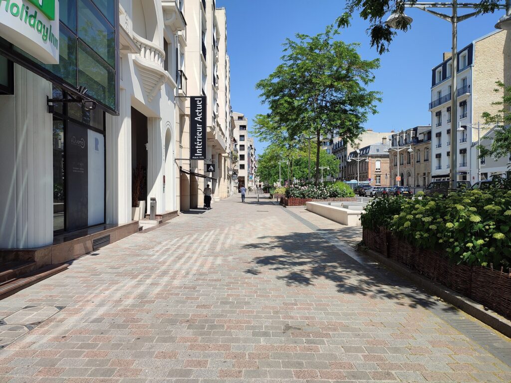 Une rue pavée du centre de Reims bordée de façades claires